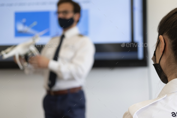 Male with a medical face mask holding a white drone during a presentation