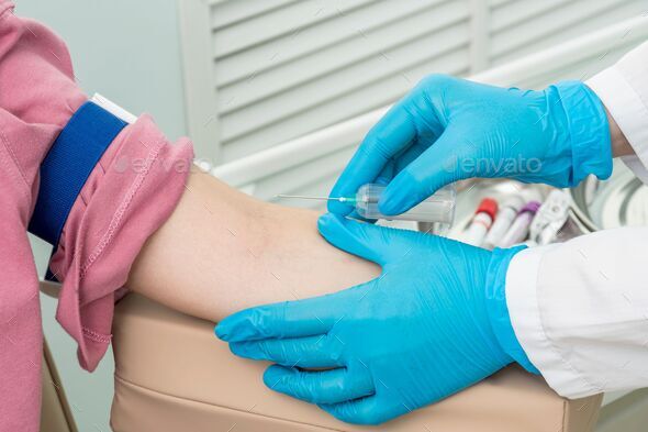 Hands of nurse in gloves insert needle into patient\'s left arm for blood sampling.