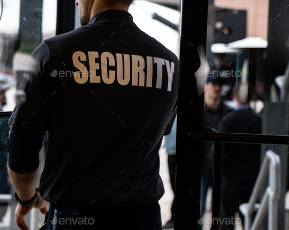 Rear view of a security guard in uniform patrolling in a commercial mall