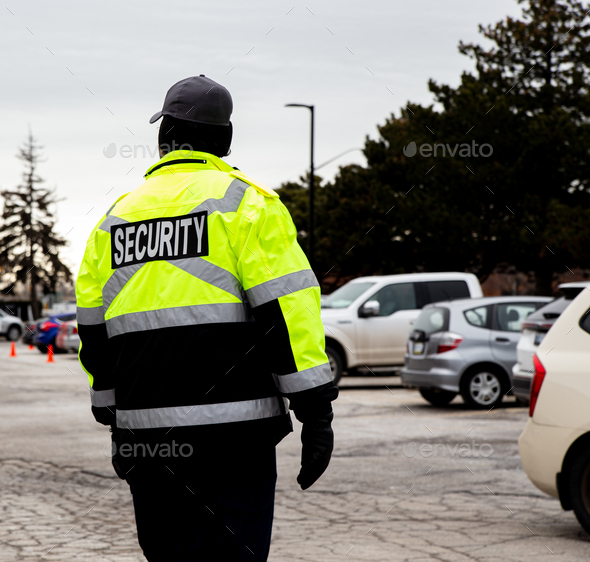 Rear view of a security guard watching over the parking area Stock