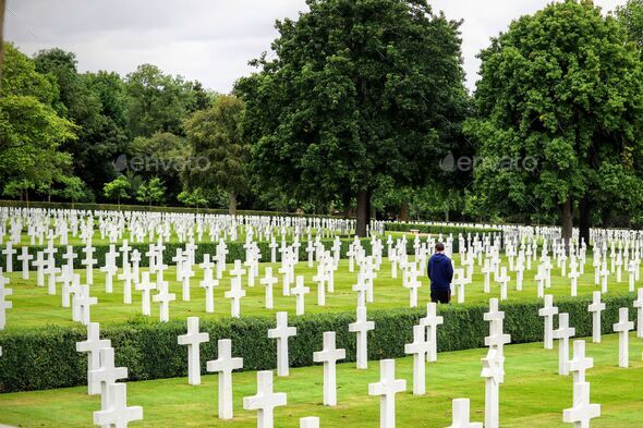 Man mourning a lost loved one in a graveyard with white crosses standing out in the green field