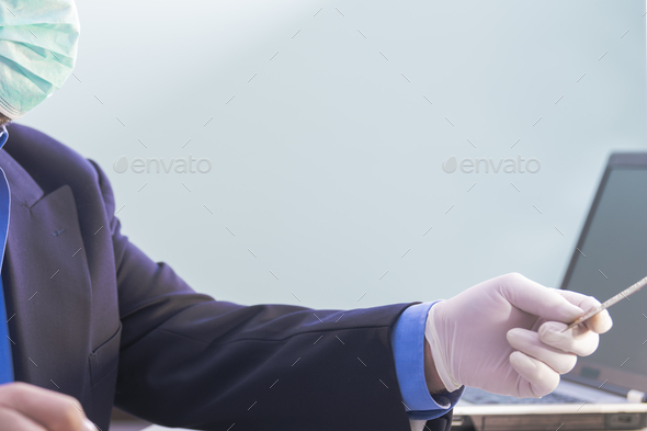 Man in a suit using and medical mask giving a credit card with his hand protected by a glove