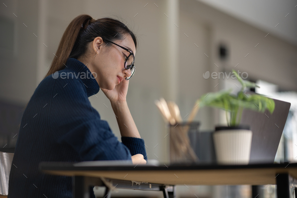 Asian women sitting in an office With stress and eye strain Tired, portrait of sad unhappy tired