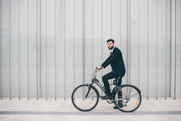 Contemporary bearded young stylish businessman going to work by bike - Stock Photo - Images
