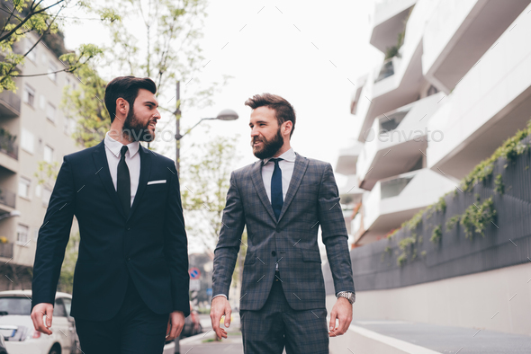 Two young elegant businessmen walking outdoors together - Stock Photo - Images