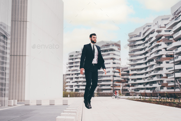 Energetic young bearded professional businessman jumping in mid-air - Stock Photo - Images