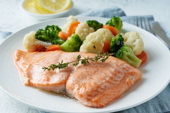 Closeup of steamed salmon and vegetables on a white plate