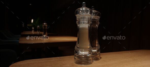 Closeup shot of salt and pepper grinders on a wooden table in a restaurant