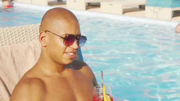 Relaxed Handsome African Man Sipping His Cocktail By the Swimming Pool