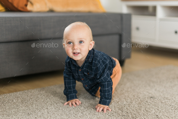 Nursery baby boy crawling on floor indoors at home copy space and empty ...