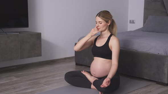 Pregnant Woman Adjusts Her Breathing for Proper Meditation a Relaxed Woman in Sports Clothes Does