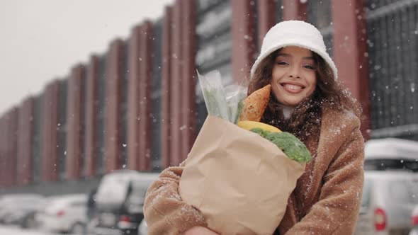 A Woman is Standing Near a Supermarket and Looking at the Camera alt