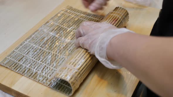 Sushi Chef Works With Bamboo Mat Wrapping It With Stretch
