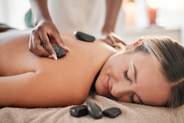 Woman, hot stone massage and masseuse, hand and zen with holistic therapy and spa treatment for bac