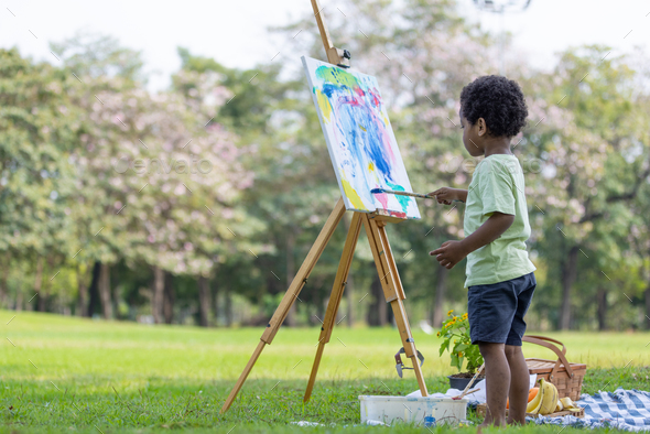 Cute little boy painting at the park  - Stock Photo - Images