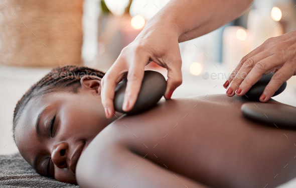 Black woman, hot stone massage, spa and hands of masseuse, holistic and wellness, therapy and treat