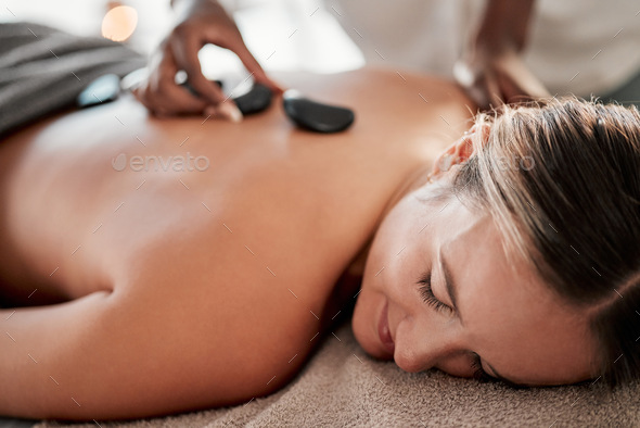 Woman, hot stone massage and masseuse, hands and zen with holistic therapy and spa treatment for ba