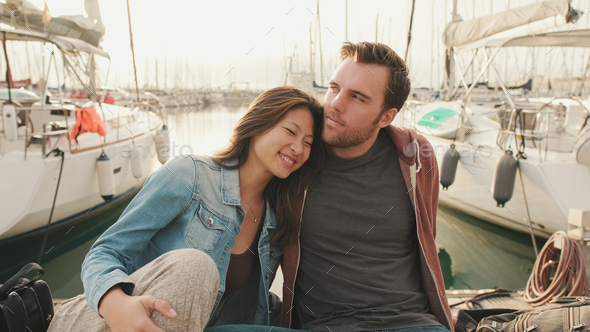 Close-up of young happy couple sitting in seaport - Stock Photo - Images