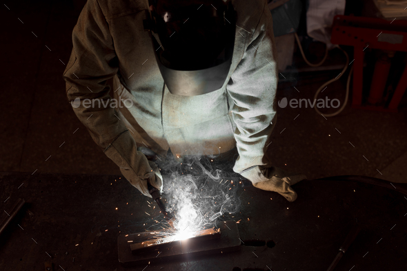high angle view of worker in protection mask welding metal at factory