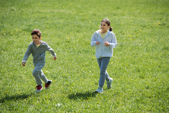 sister and brother running on meadow in park Stock Photo by ...