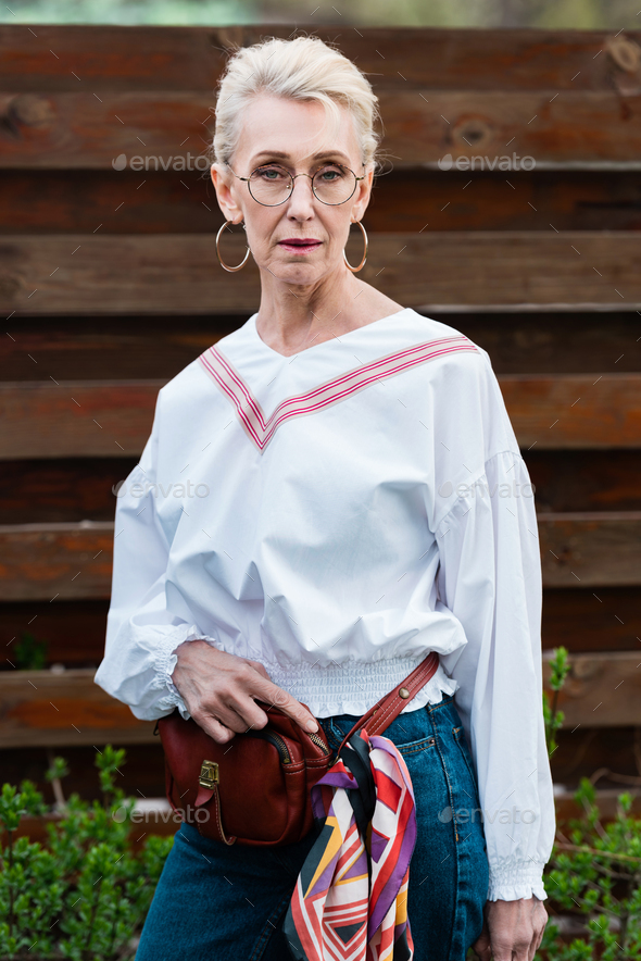 beautiful senior woman posing in stylish outfit with waist bag