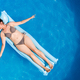 Young woman in bikini on Air Mat Mattress in round above ground swiming pool. Top view - PhotoDune Item for Sale