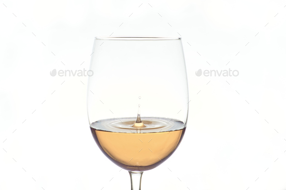 Wine drop falls into white wine glass on white background.