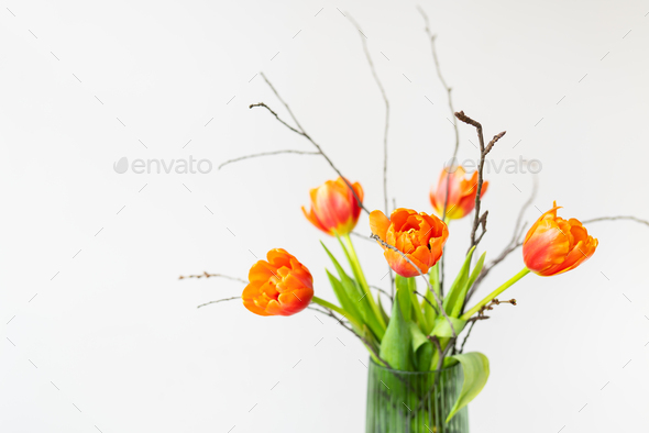 A very beautiful spring bouquet in a green vase stands on a table on a linen tablecloth, orange