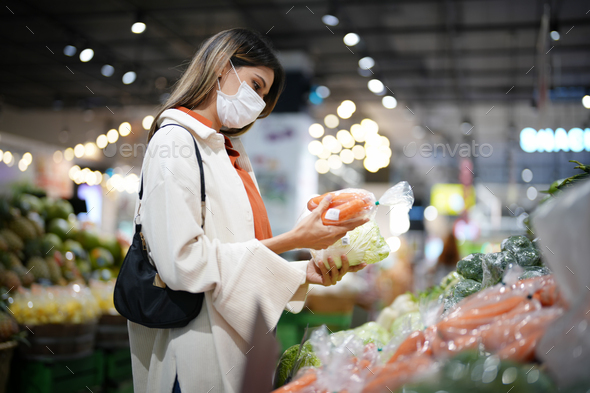 Side profile of beautiful young Asian woman shopping for daily necessities in supermarket.