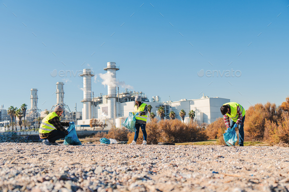 Team of environmental volunteer activist picking up plastic trash of the sand on the beach near a