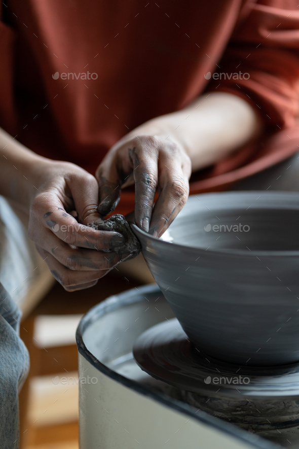 Artisan woman hands shaping deep plate made of natural clay placed on spinning potter whee - Stock Photo - Images