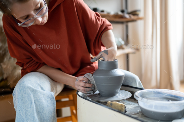 Craftswoman enjoying meditative process of making ceramics, shaping clay on pottery wheel - Stock Photo - Images