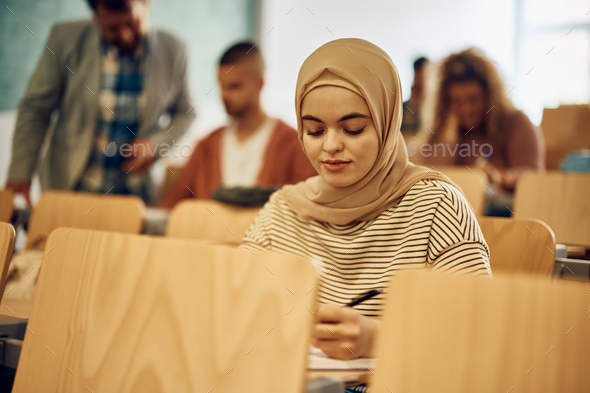 Female Muslim student writing an exam at the university.