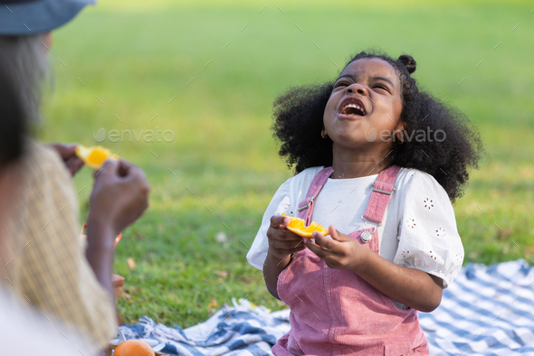 A curly hair children eating orange with be happiness - Stock Photo - Images