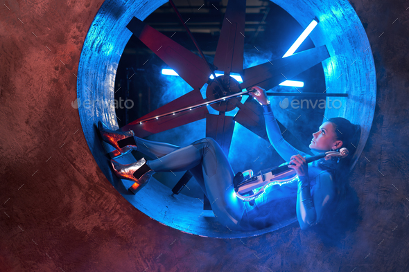 Violinist with instrument on industrial air blower turbine