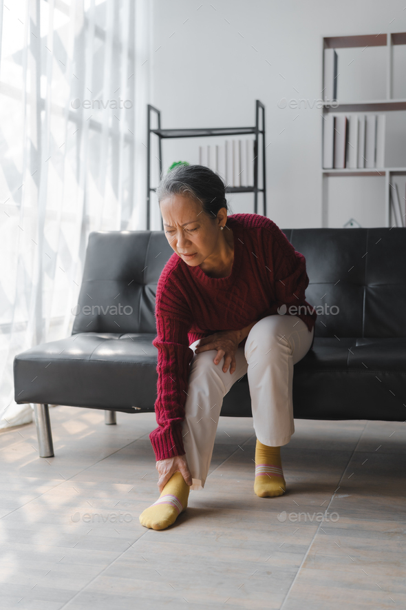 Elderly asian housewife woman sitting on sofa. heel pain or foot pain