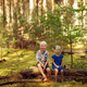 happy cute kids sitting together in forest and looking at camera. - PhotoDune Item for Sale