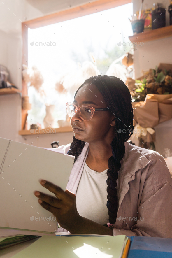 Woman with braided hair at her home office looking through the documents - Stock Photo - Images