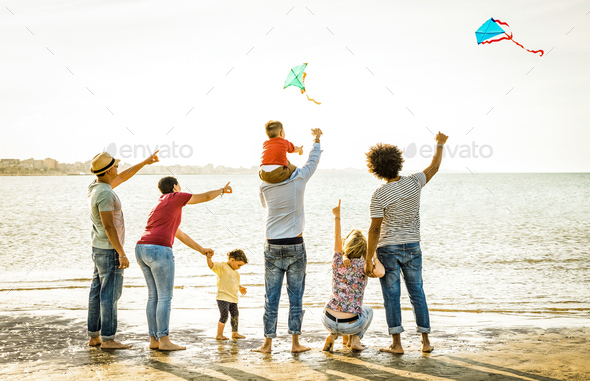 Happy families group with parents and children playing with kite at beach vacation - Stock Photo - Images