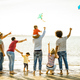 Happy families group with parents and children playing with kite at beach vacation - PhotoDune Item for Sale