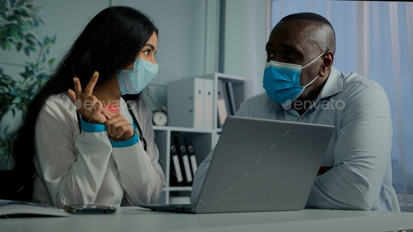 Young doctor woman talk with old man patient in mask use laptop check electronic health test result