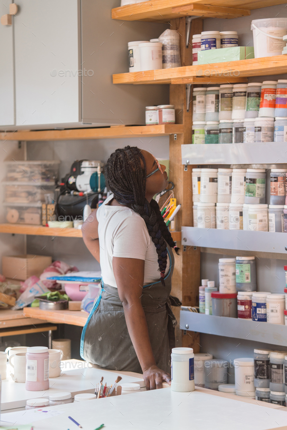 Female ceramic artist looking through the paints at her art studio - Stock Photo - Images