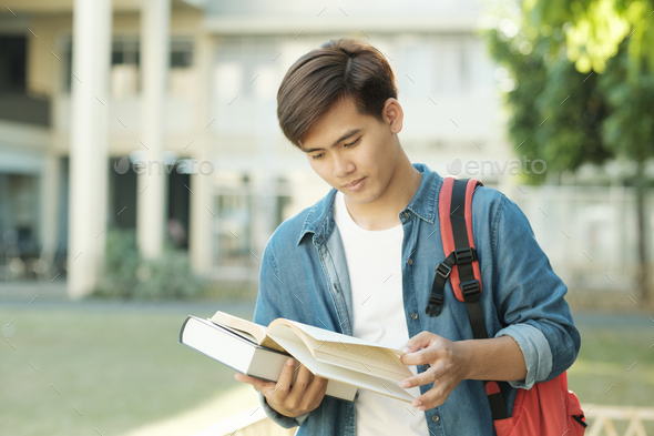 Student standing outdoor and holding books. - Stock Photo - Images