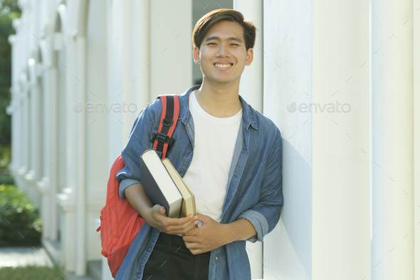 Student standing outdoor and holding books. - Stock Photo - Images