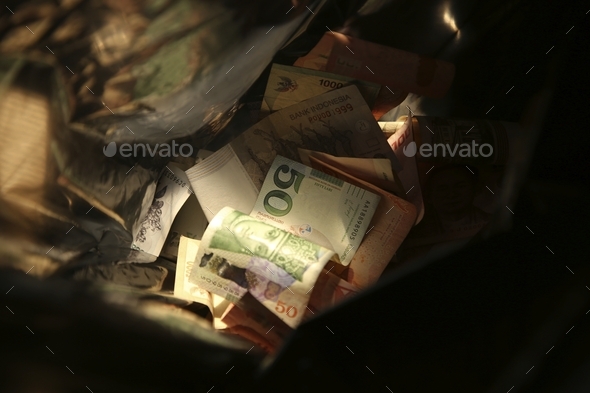 High angle closeup shot of cash money in a black trash bag