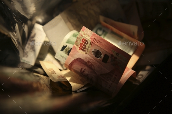 High angle closeup shot of cash money in a black trash bag
