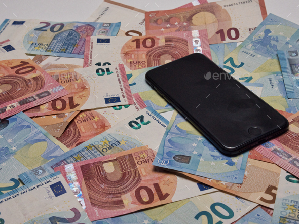 Closeup shot of a pile of ten and twenty Euro banknotes and a smartphone