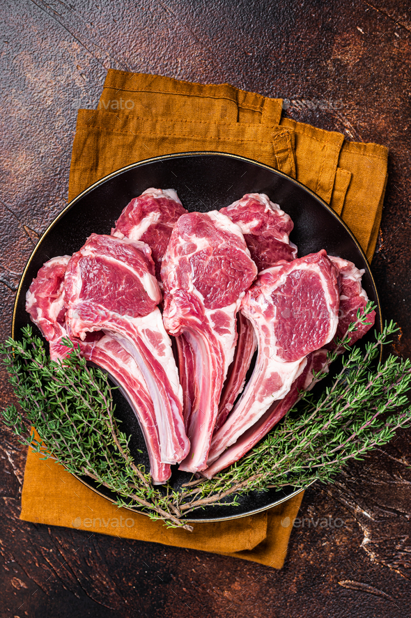 Raw lamb chops, fresh mutton meat cutlets on a ribs. Dark background