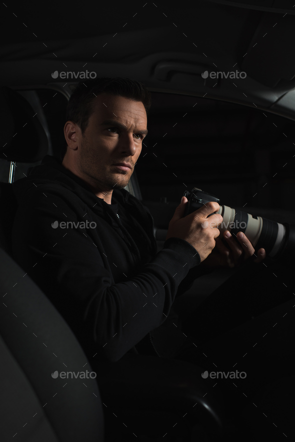 undercover male agent doing surveillance by camera with lens from car Stock  Photo by LightFieldStudios
