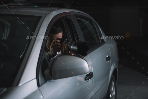 undercover male agent doing surveillance by camera with lens from car Stock  Photo by LightFieldStudios